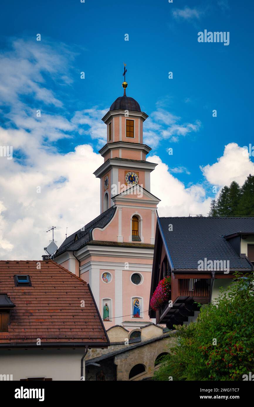 Il campanile della chiesa si affaccia su case ed edifici sormontati da vivaci tetti rossi Foto Stock