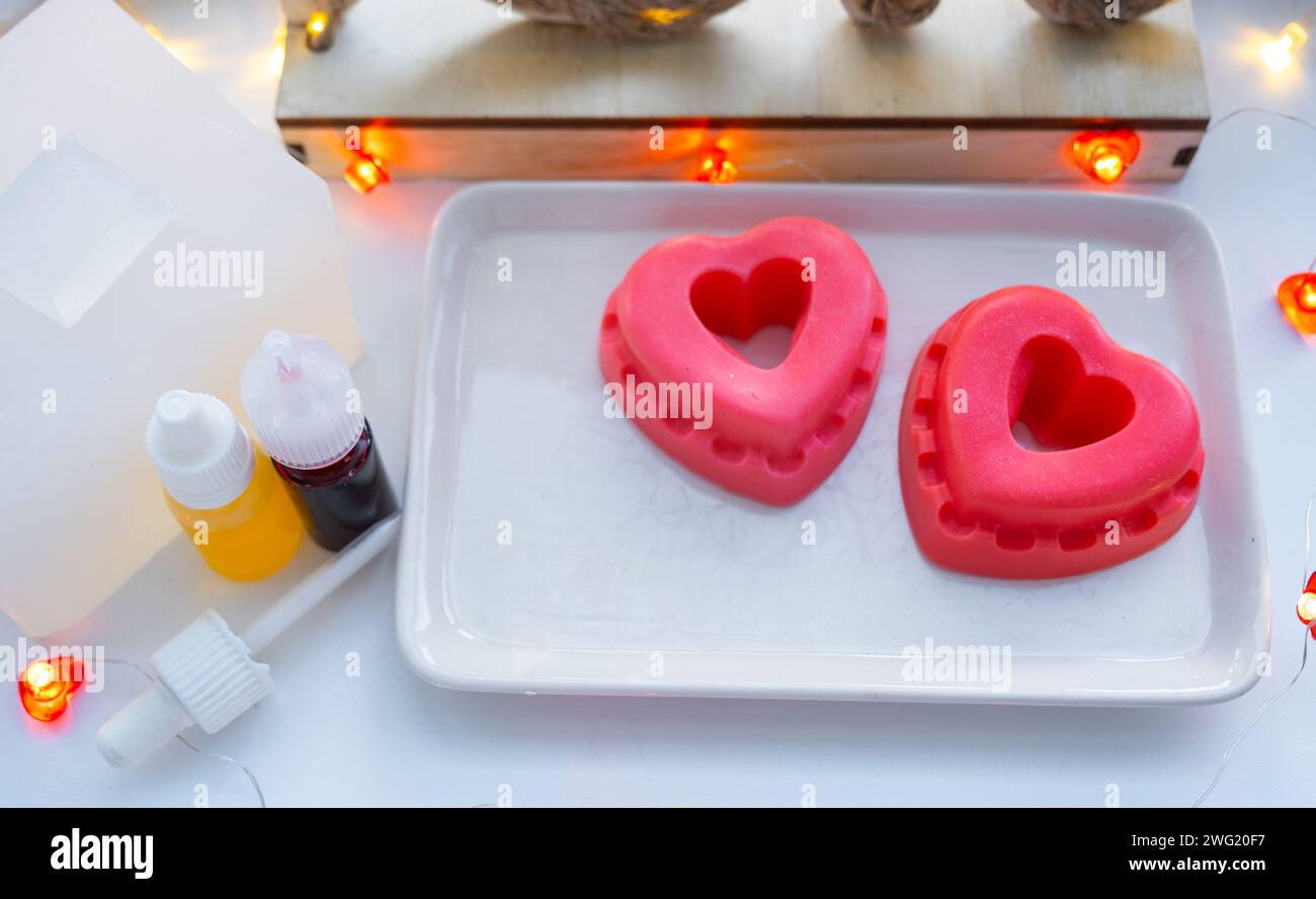 Sapone fatto a mano a forma di cuori per un regalo di San Valentino alla tua amata. Profumi e coloranti, base di sapone sul tavolo Foto Stock