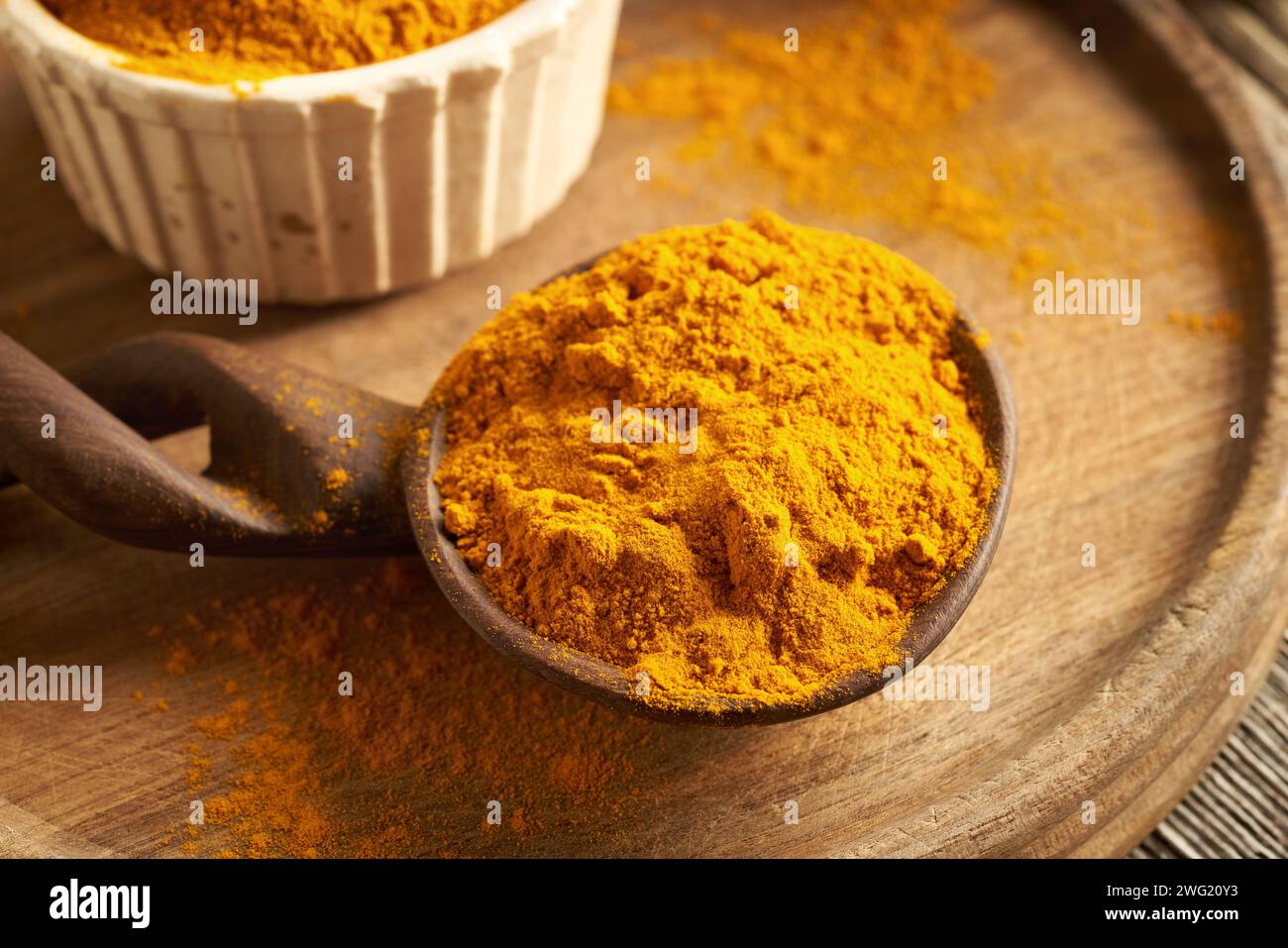 Polvere di radice di curcuma essiccata su un cucchiaio di legno su un tavolo Foto Stock