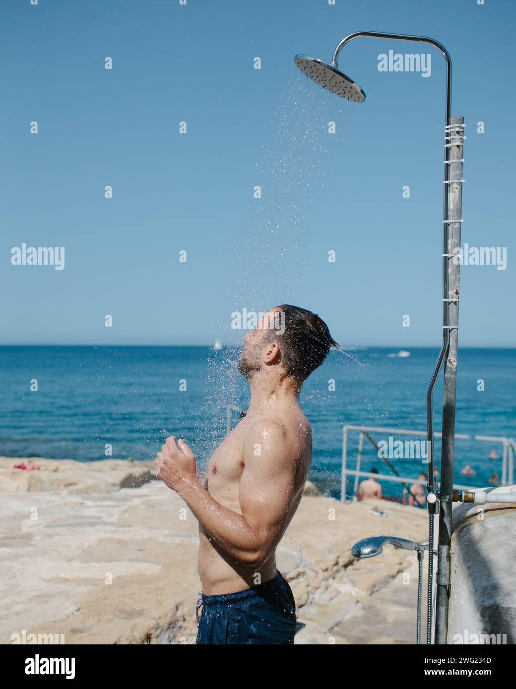 Un uomo si lava sotto una doccia sulla spiaggia di Malta. Foto Stock