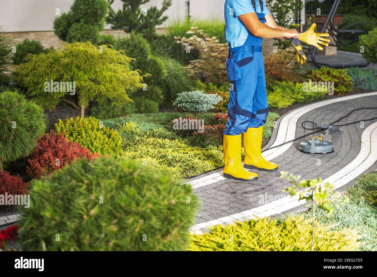 Backyard Brick paths lavaggio a pressione eseguito da un lavoratore Foto Stock