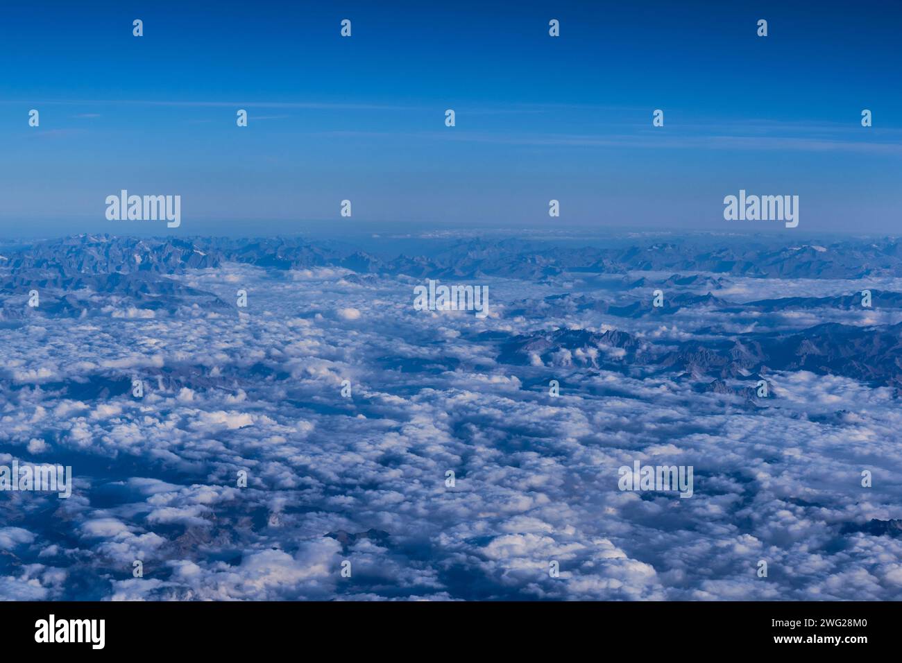 Vette di montagna viste attraverso le nuvole dall'aereo Foto Stock