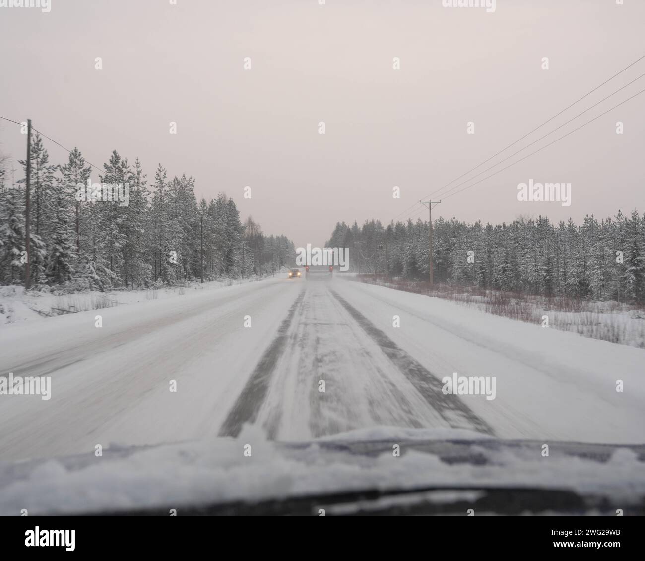 Una strada ghiacciata e innevata a Paltamo, in Finlandia, in inverno. Le condizioni stradali sembrano ghiacciate e pericolose. Foto Stock