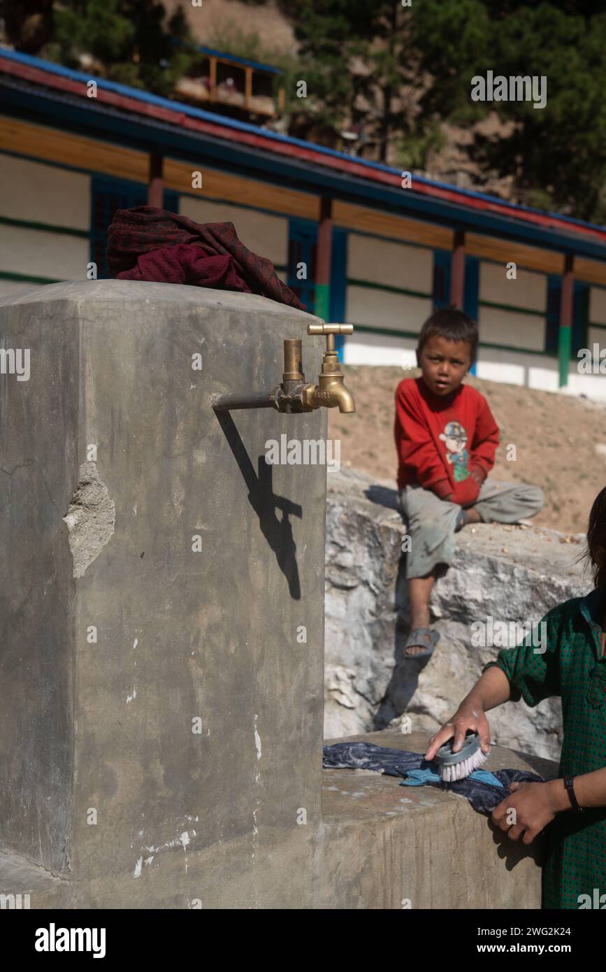 Bambini nepalesi che lavano e bevono in una fonte di acqua di villaggio/comunità a Palata, distretto di Dolpa, Nepal occidentale, 2023. Foto Stock