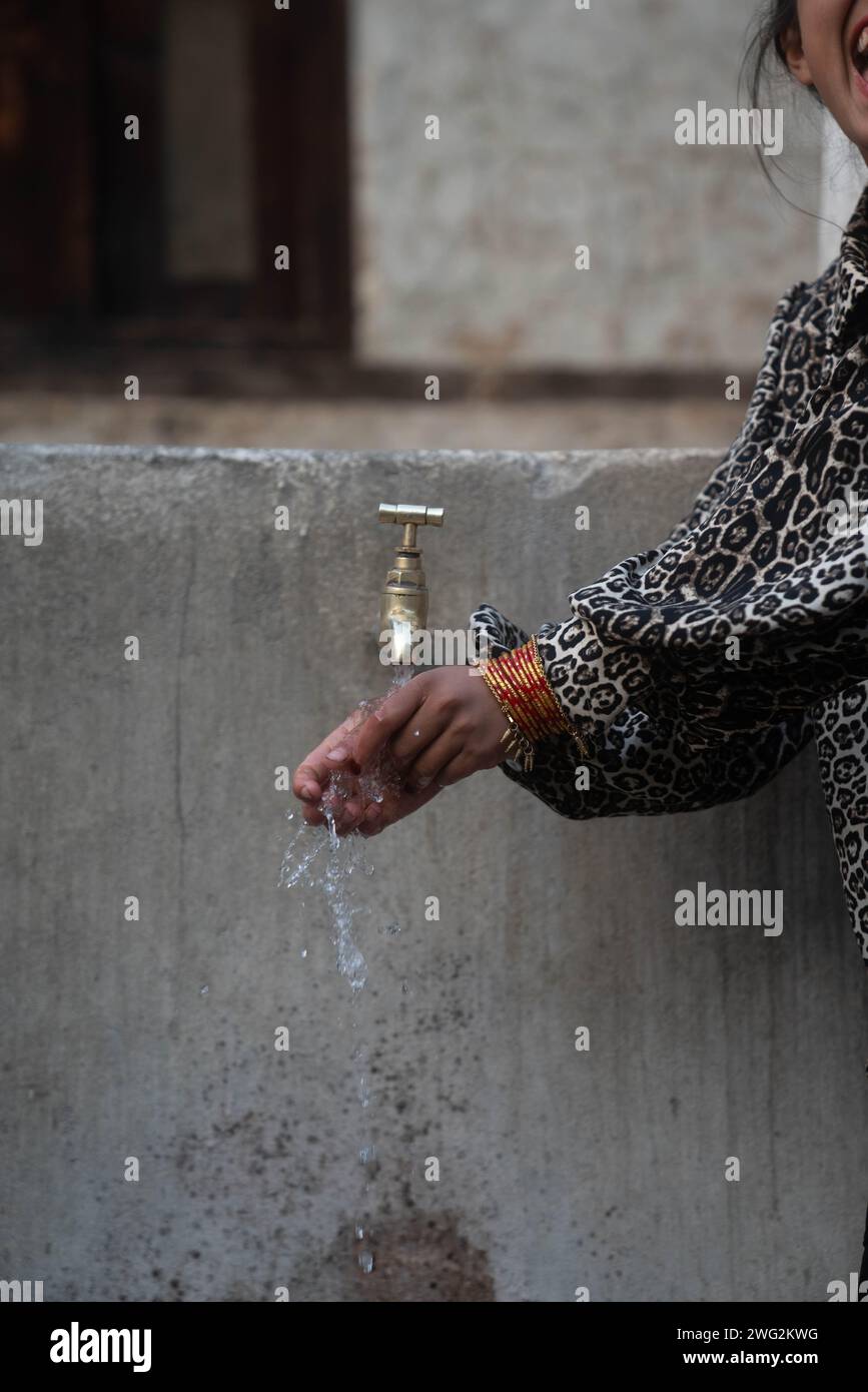 Bambini nepalesi che lavano e bevono in una fonte di acqua di villaggio/comunità a Palata, distretto di Dolpa, Nepal occidentale, 2023. Foto Stock