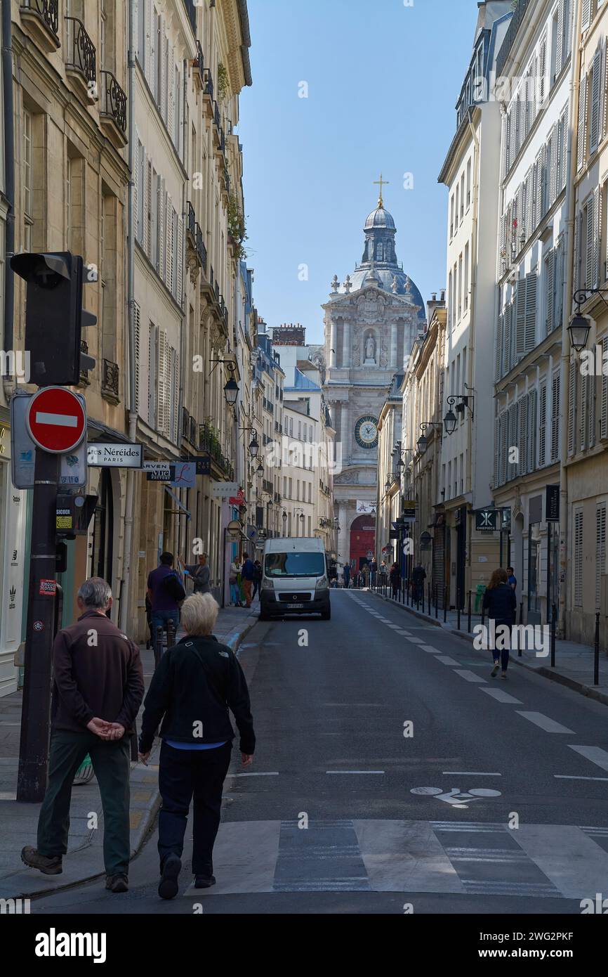 Due uomini che passeggiano per una strada cittadina mentre un'auto passa davanti a loro Foto Stock
