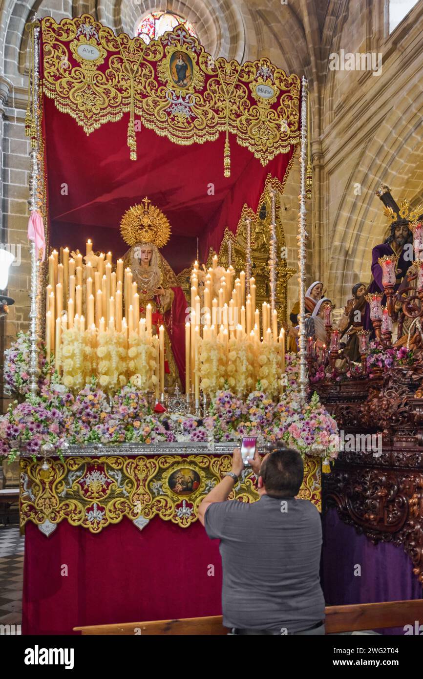 Jerez de la Frontera, Spagna - 2 febbraio 2024: Uomo con grande devozione davanti ad un pass della settimana Santa che scatta una fotografia della Vergine con il suo cellulare Foto Stock