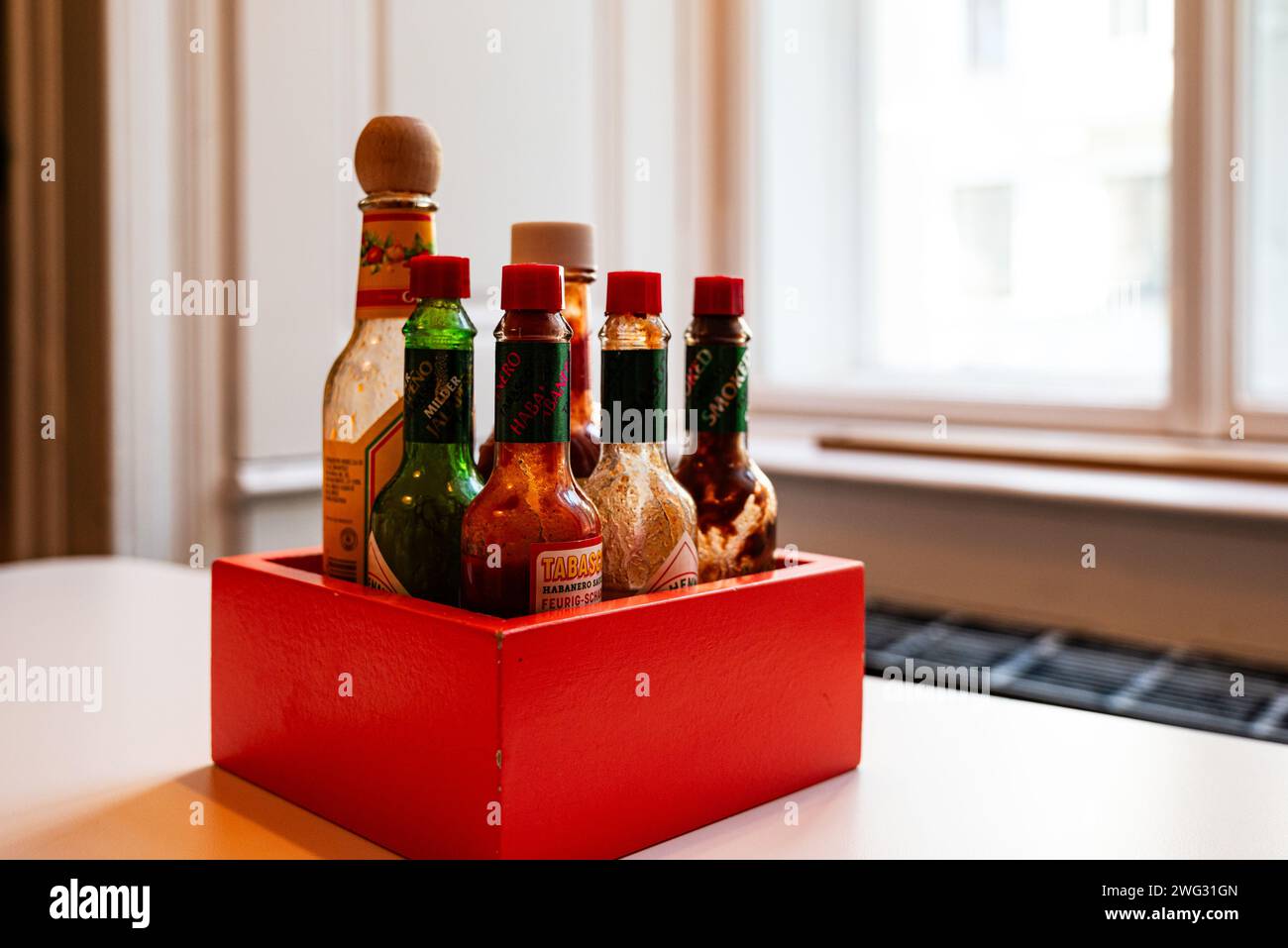 Scatola rossa di salse al peperoncino e altri condimenti su un tavolo in un bar di taco Foto Stock