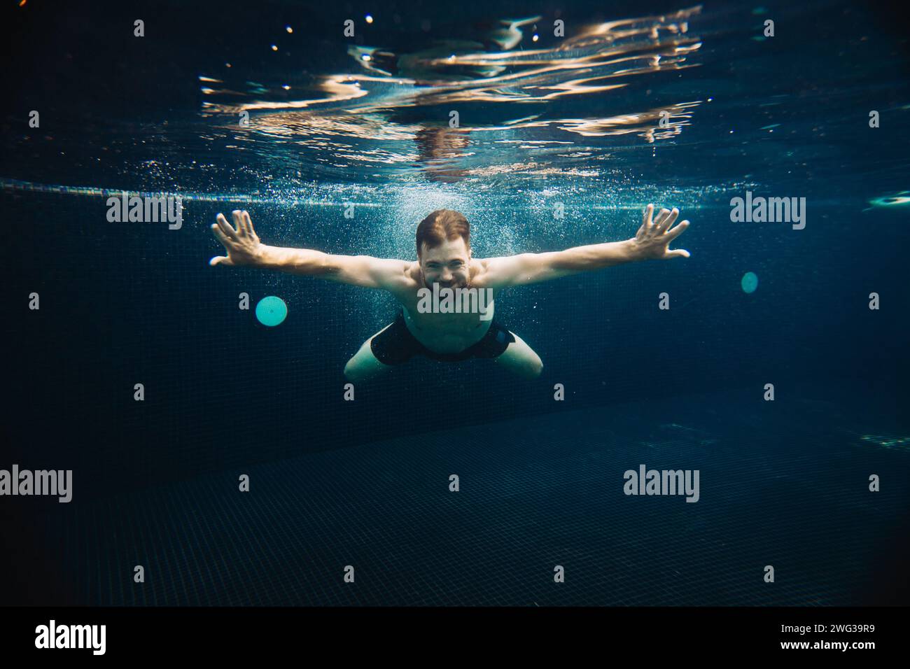 Un giovane nuota sott'acqua in una piscina. Concetto di vacanza estiva. Foto Stock