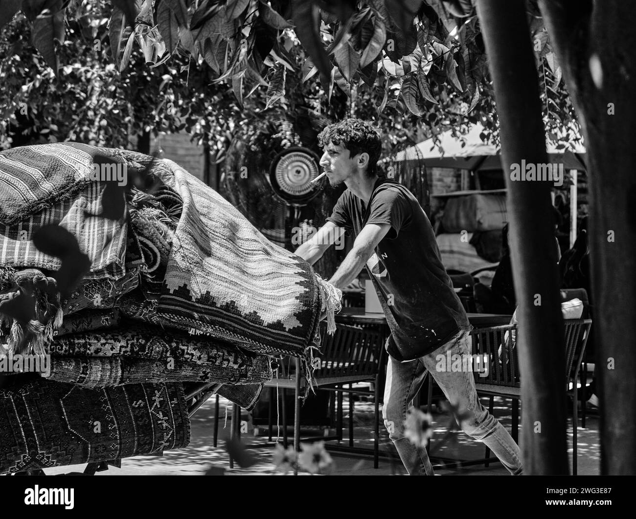 Shiraz, Iran - 06.26.2023: Un uomo iraniano, un lavoratore, porta tappeto a carriola. Foto in bianco e nero dell'iran. Foto Stock