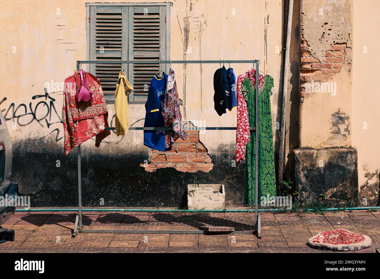 Il bucato si asciugava all'esterno di fronte a un muro intemprato sul lato della strada di Kampot Cambogia, mostrando la genuina vita quotidiana e la cultura khmer Foto Stock