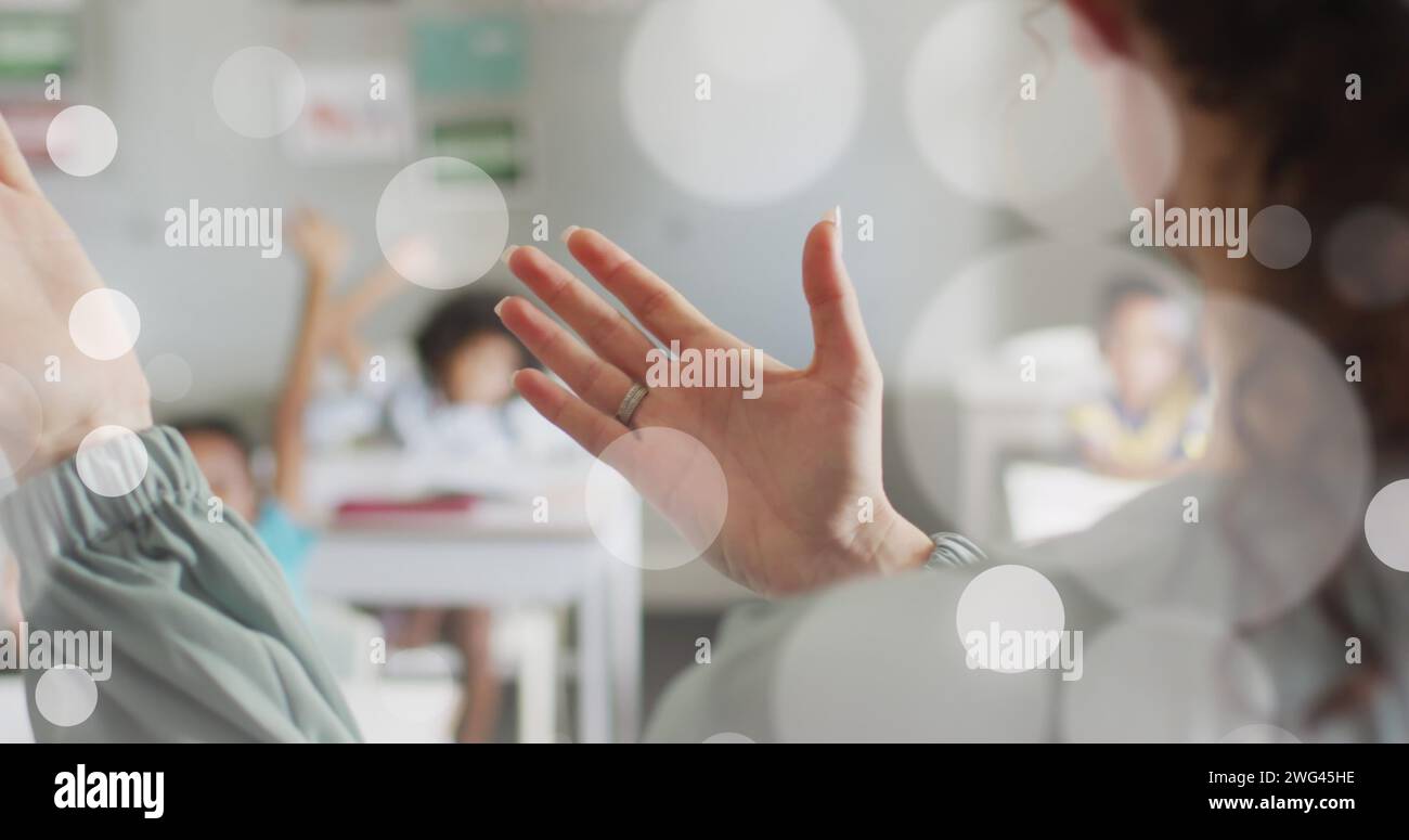 Immagine di macchie bokeh bianche sulle mani di diverse insegnanti e alunni in classe Foto Stock