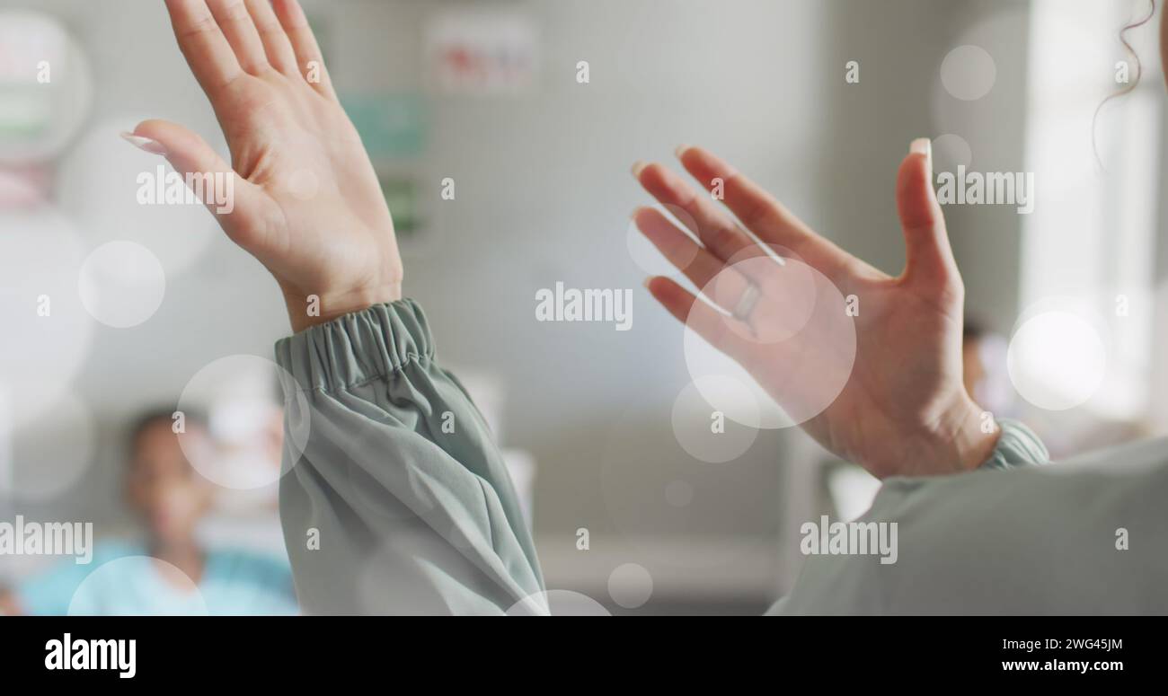 Immagine di macchie bokeh bianche sulle mani di diverse insegnanti e alunni in classe Foto Stock