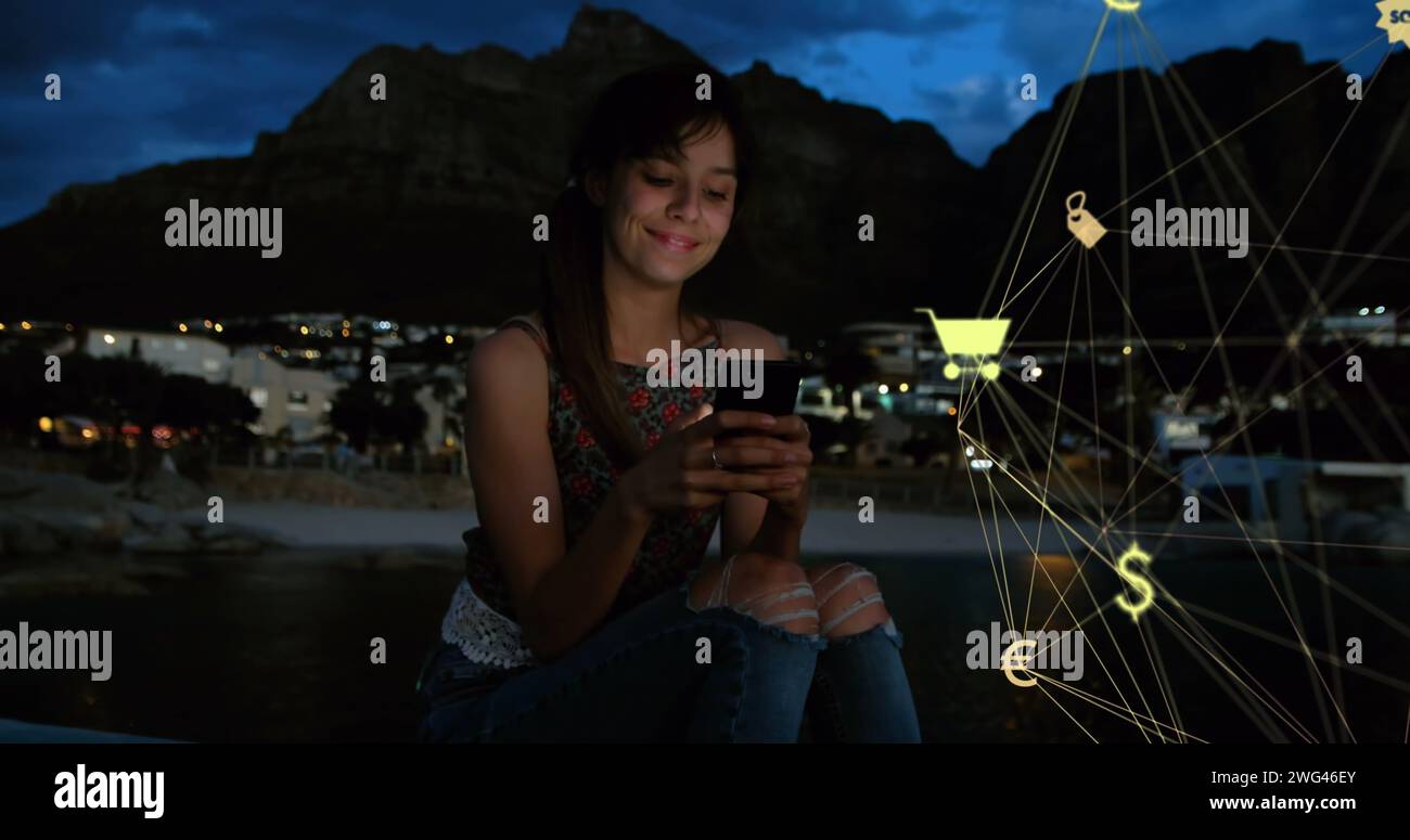 Globo di icone digitali che si scontrano con il caucasico utilizzando lo smartphone all'aperto di notte Foto Stock