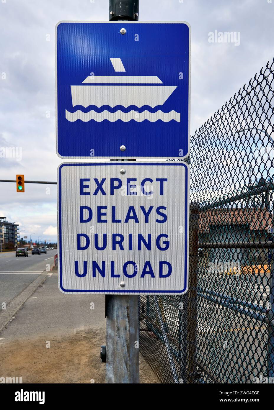 Un cartello blu e bianco con l'indicazione "attesa ritardi durante lo scarico" Foto Stock