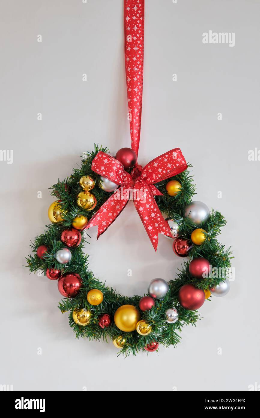 Corona di Natale con nastro rosso con stelle e decorazioni con palle natalizie dorate, rosse e argento. Foto Stock