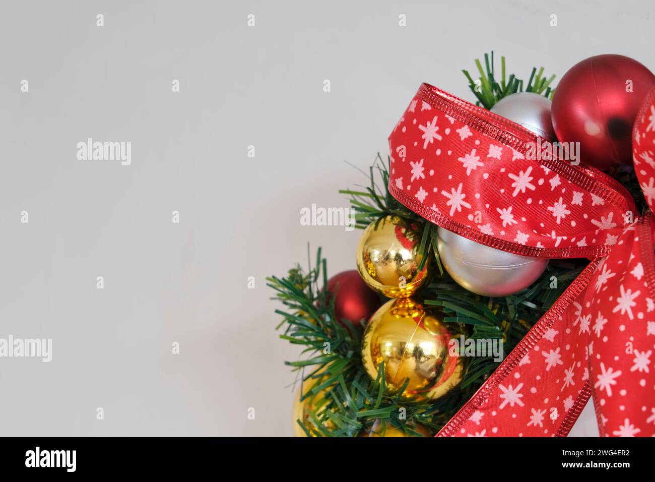Dettaglio della corona di natale con nastro rosso con stelle e decorazioni con palle di natale dorate, rosse e argento. Immagine con spazio di copia Foto Stock