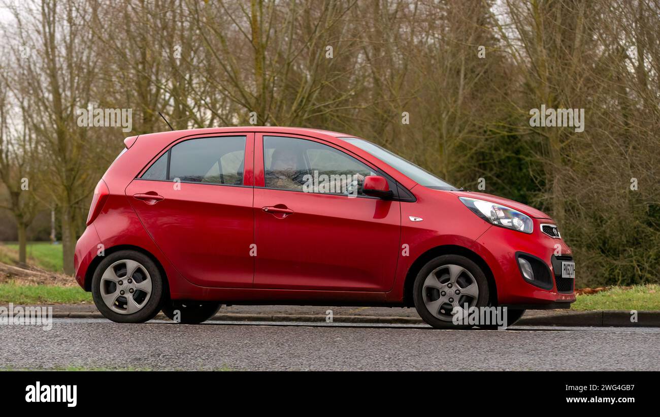 Milton Keynes, Regno Unito - 2 febbraio 2024: 2012 auto Kia Picanto rossa che guida su una strada di campagna inglese. Foto Stock