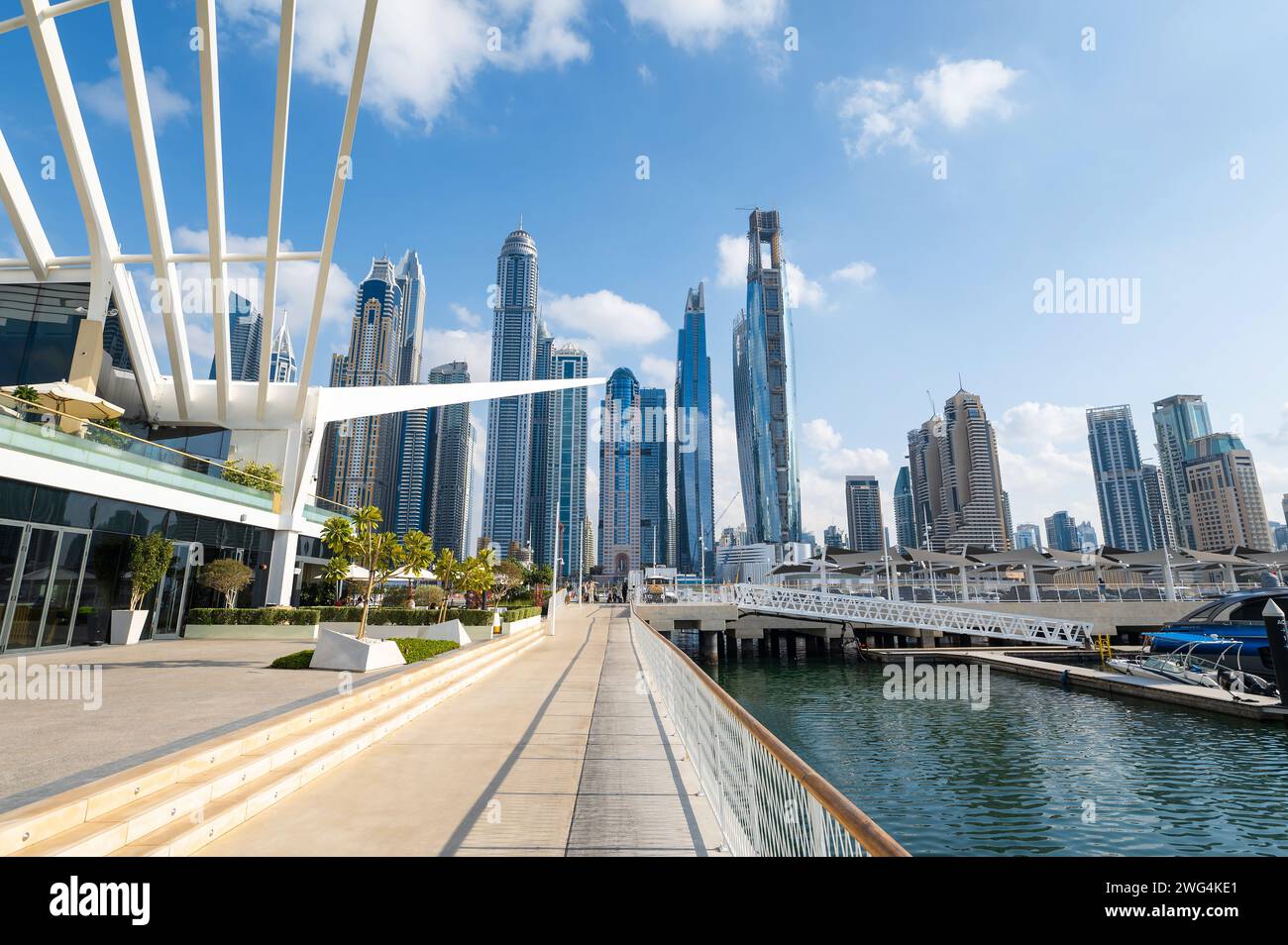 Porto turistico di Dubai in una giornata di sole negli Emirati Arabi Uniti, con una vivace metropoli, incontra acque tranquille mentre le barche navigano sotto un maestoso skyline della città, incorniciato da Foto Stock