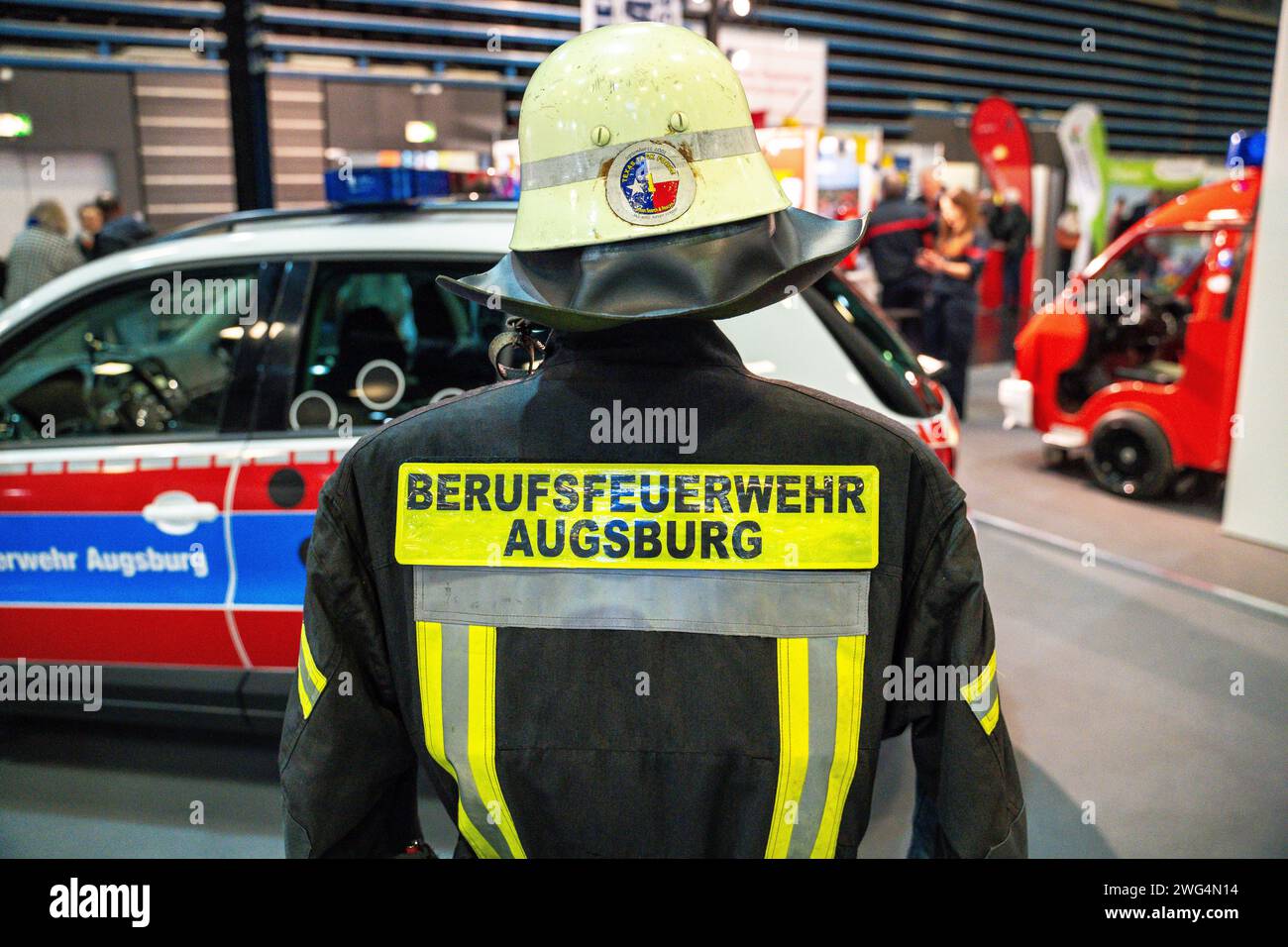 Augusta, Baviera, Germania - 2 febbraio 2024: Stand dei vigili del fuoco di Augusta alla fiera AFA. Vigili del fuoco con camion antincendio, abbigliamento protettivo e uniforme *** Messestand der Berufsfeuerwehr Augsburg auf der AFA-Messe. Feuerwehr mit Feuerwehrauto, Schutzkleidung und Uniform Foto Stock