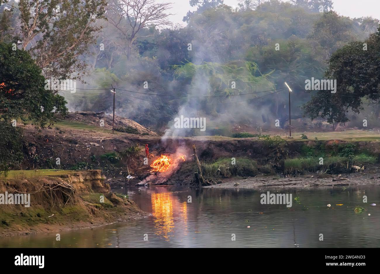 Le tradizionali pire di cremazione funebre indù bruciano a Jagaddal Ghat sulle rive del fiume Hoostly al crepuscolo a North Barrackpore, Bengala Occidentale, India Foto Stock