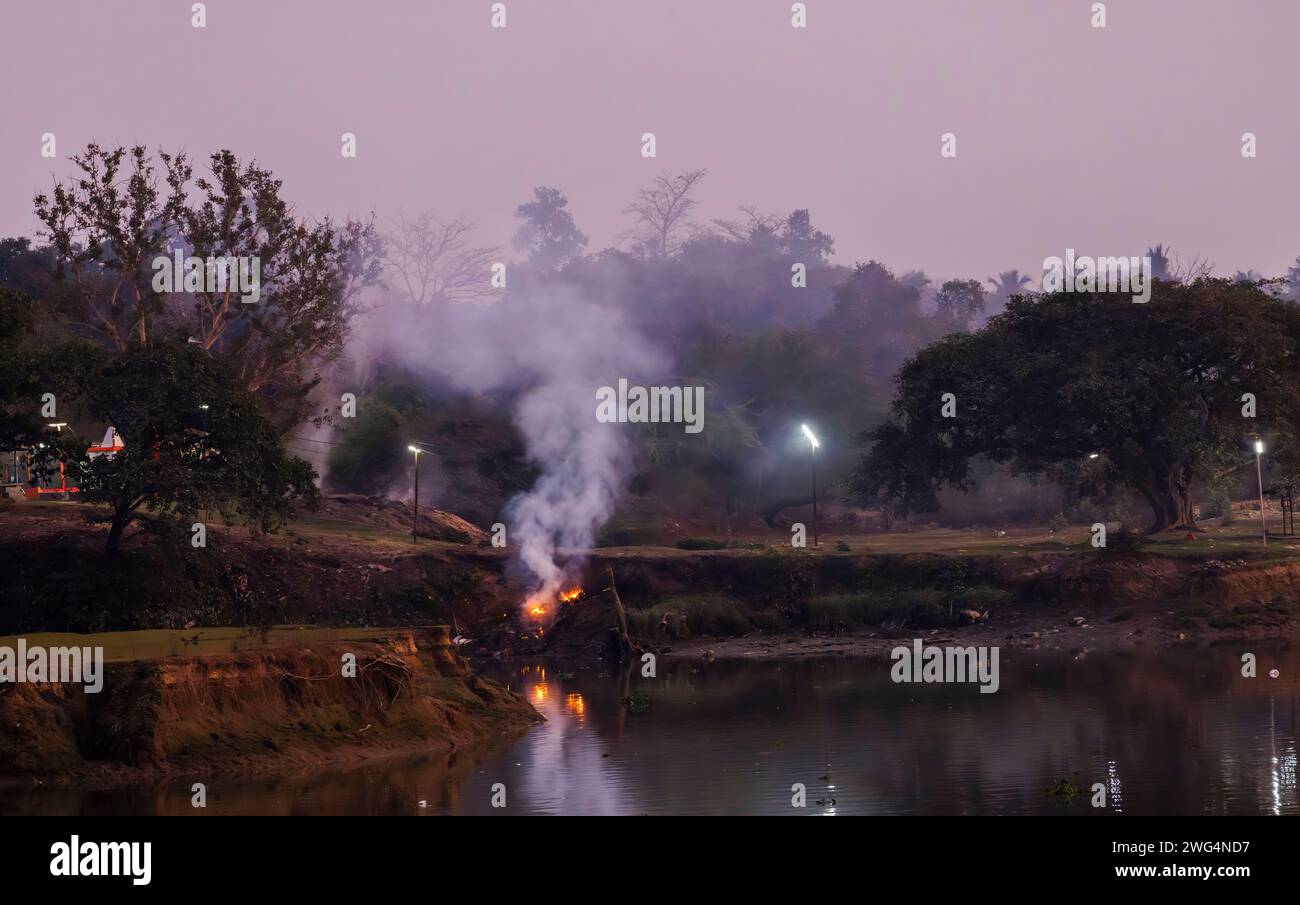 Le tradizionali pire di cremazione funebre indù bruciano a Jagaddal Ghat sulle rive del fiume Hoostly al crepuscolo a North Barrackpore, Bengala Occidentale, India Foto Stock
