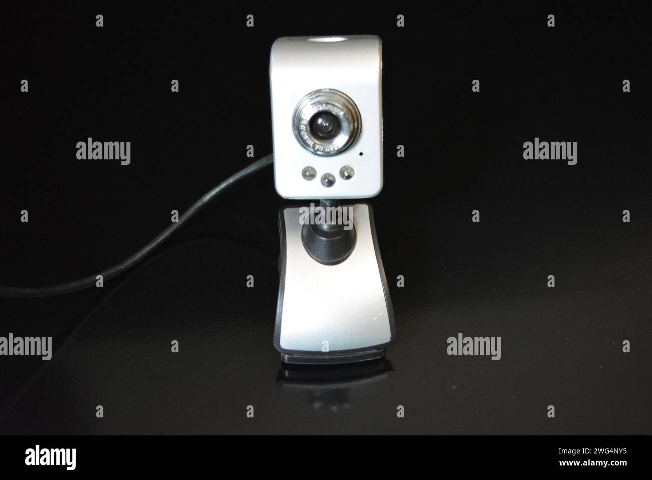 Una webcam color argento per il computer con clip per il monitor si trova su una superficie nera opaca con riflesso. Foto Stock