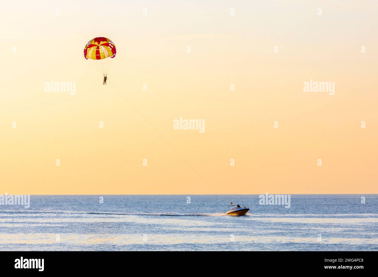 Due paracadutisti contro un tramonto serale sull'isola di Phu Quoc, in Vietnam trainati da un motoscafo Foto Stock