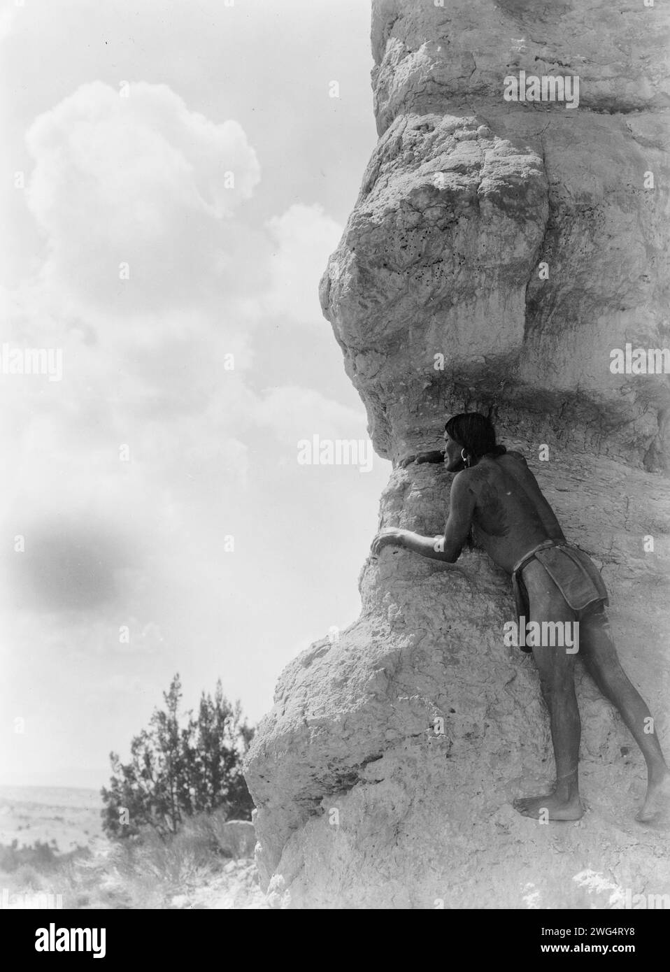 La sentinella-San Ildefonso, c1927. San Ildefonso uomo che pesa da dietro una grande formazione rocciosa. Foto Stock