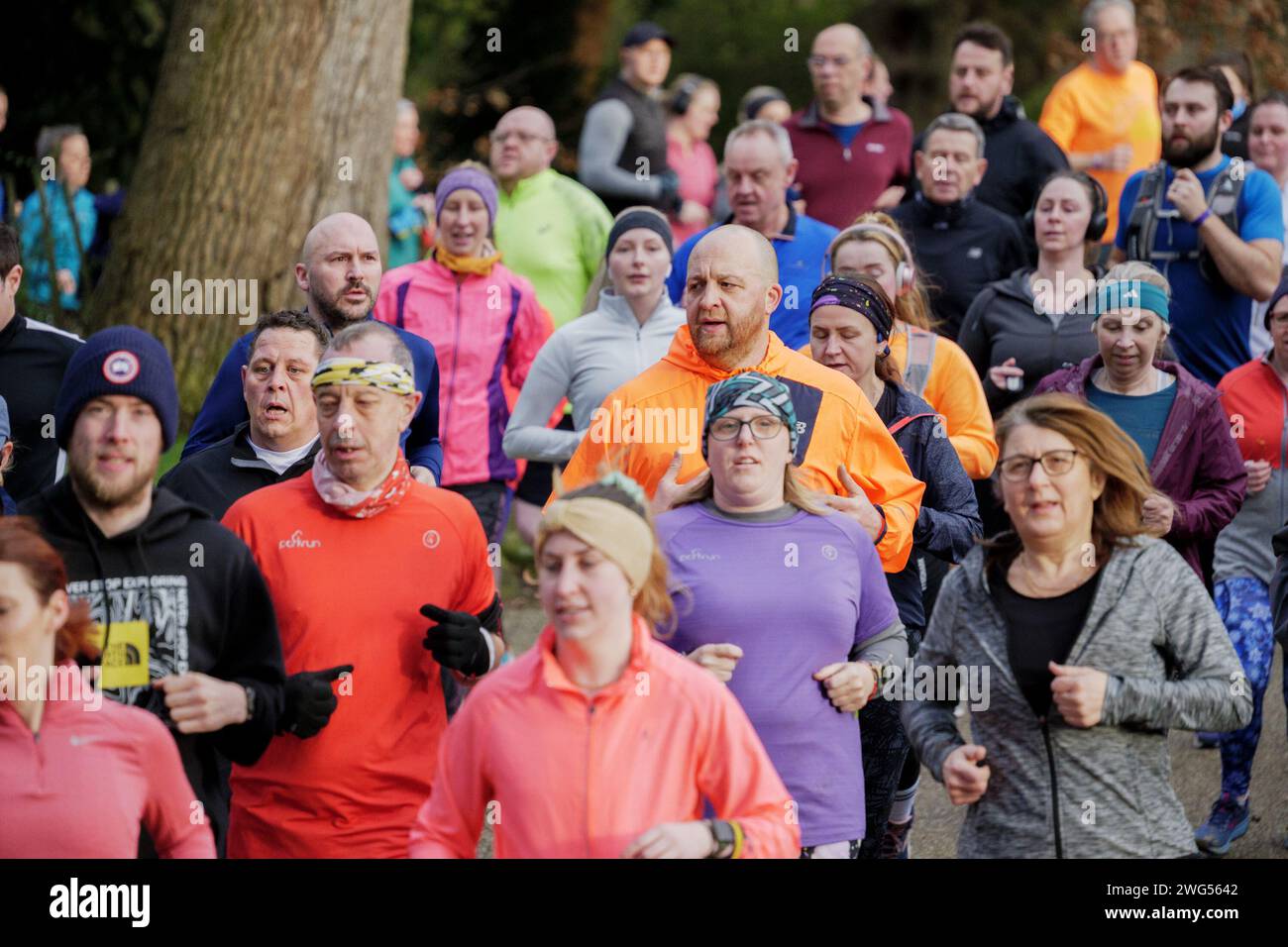 Corridori che corrono a Bradford con alcuni che indossano il verde per la giornata mondiale del cancro. Il Park Run di 5 km si svolge a Robert's Park, Shipley, West Yorkshire. Foto Stock
