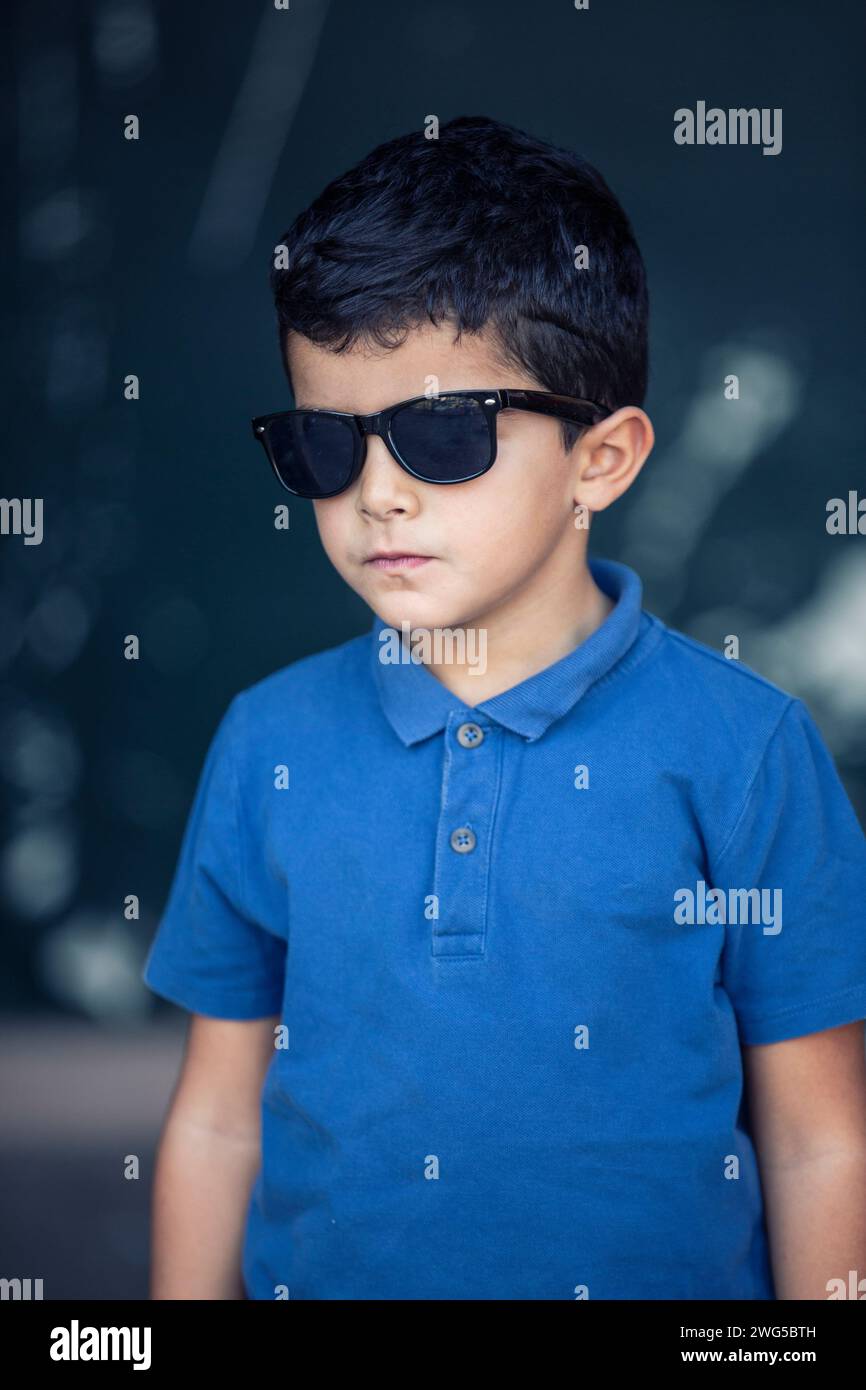 sei anni, ragazzo medio-orientale che indossa gli occhiali da sole all'aperto Foto Stock