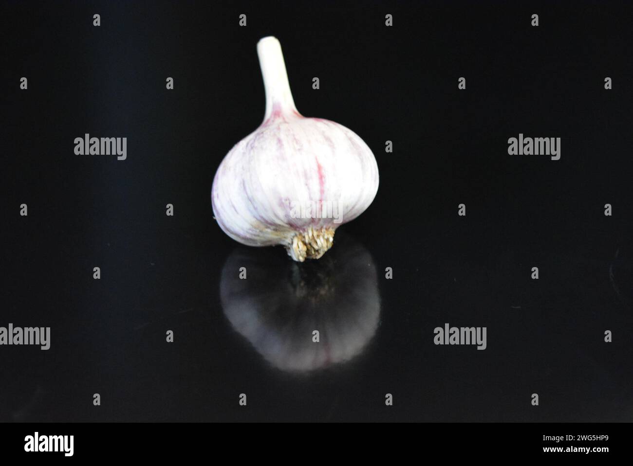 Verdure fresche, tre teste di vitello adagiate su una superficie nera lucida con riflessi ripetuti. Foto Stock