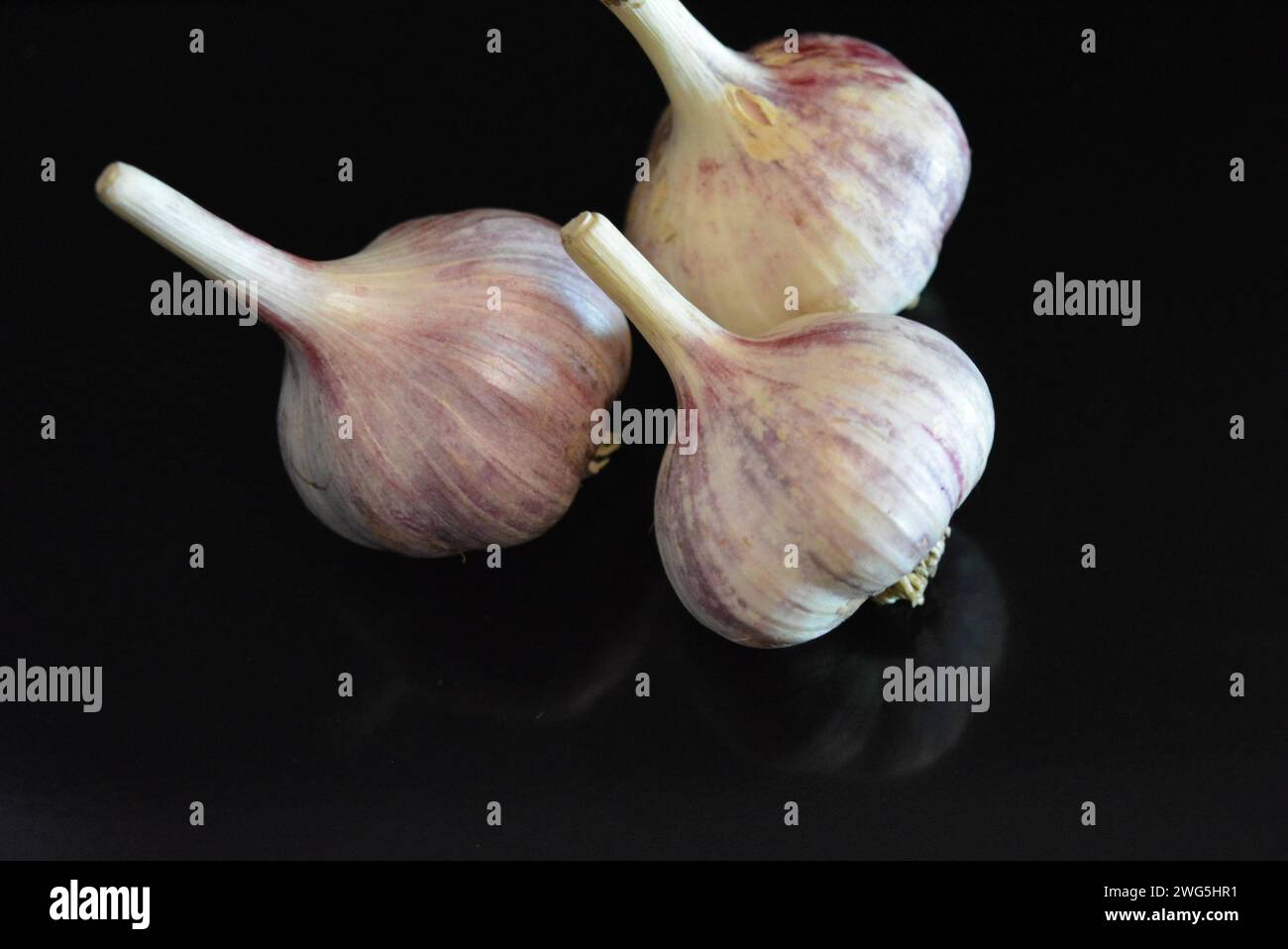 Verdure fresche, tre teste di vitello adagiate su una superficie nera lucida con riflessi ripetuti. Foto Stock