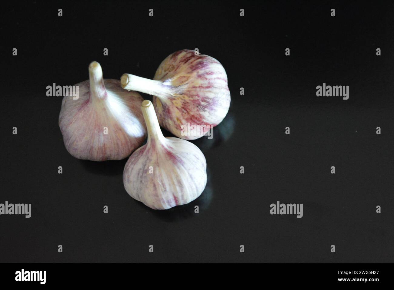 Verdure fresche, tre teste di vitello adagiate su una superficie nera lucida con riflessi ripetuti. Foto Stock