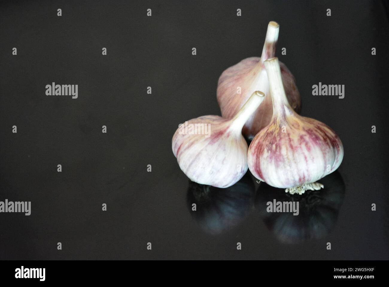 Verdure fresche, tre teste di vitello adagiate su una superficie nera lucida con riflessi ripetuti. Foto Stock