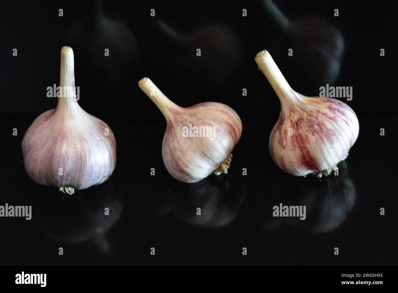 Verdure fresche, tre teste di vitello adagiate su una superficie nera lucida con riflessi ripetuti. Foto Stock