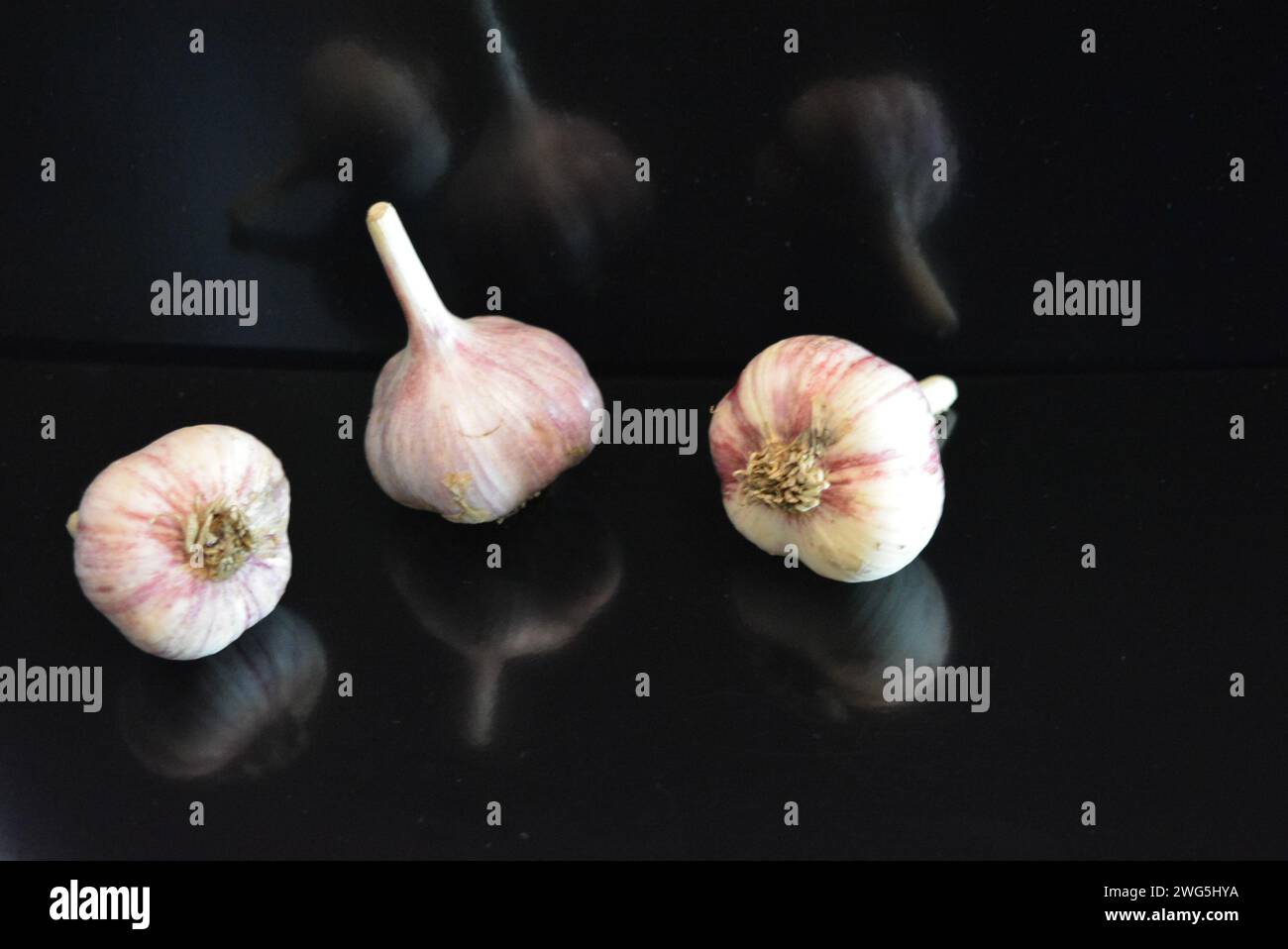 Verdure fresche, tre teste di vitello adagiate su una superficie nera lucida con riflessi ripetuti. Foto Stock