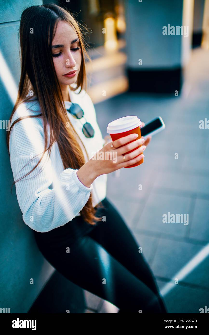 Un professionista impegnato che si appresta a fare una pausa caffè in città con lo smartphone Foto Stock