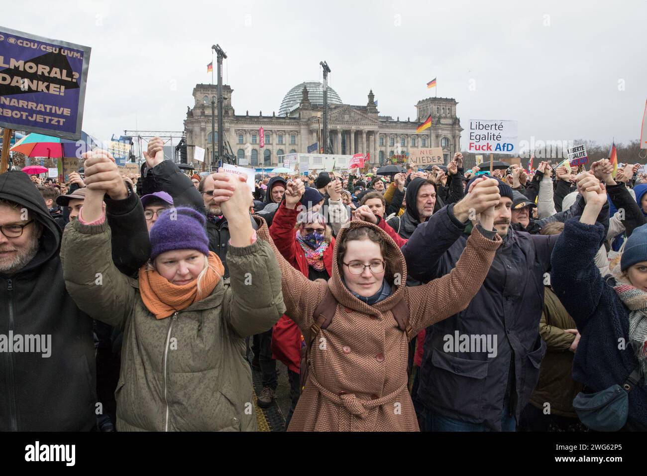 Berlino fu testimone di un monumentale raduno il 3 febbraio 2024, quando circa 300.000 manifestanti formarono un simbolico "firewall" contro l'estremismo di destra davanti al Bundestag sotto la bandiera WeAreTheFirewall. Questa massiccia mobilitazione risponde ai crescenti sentimenti di destra e alle violazioni dei diritti umani all'interno della società e della politica, sostenendo una maggiore tolleranza e una democrazia solida. Il raduno è stato organizzato dalla rete "mano in mano", che ha visto oltre 1.700 organizzazioni firmare una dichiarazione contro l'estremismo di destra, mostrando un fronte unito da un ampio spettro Foto Stock