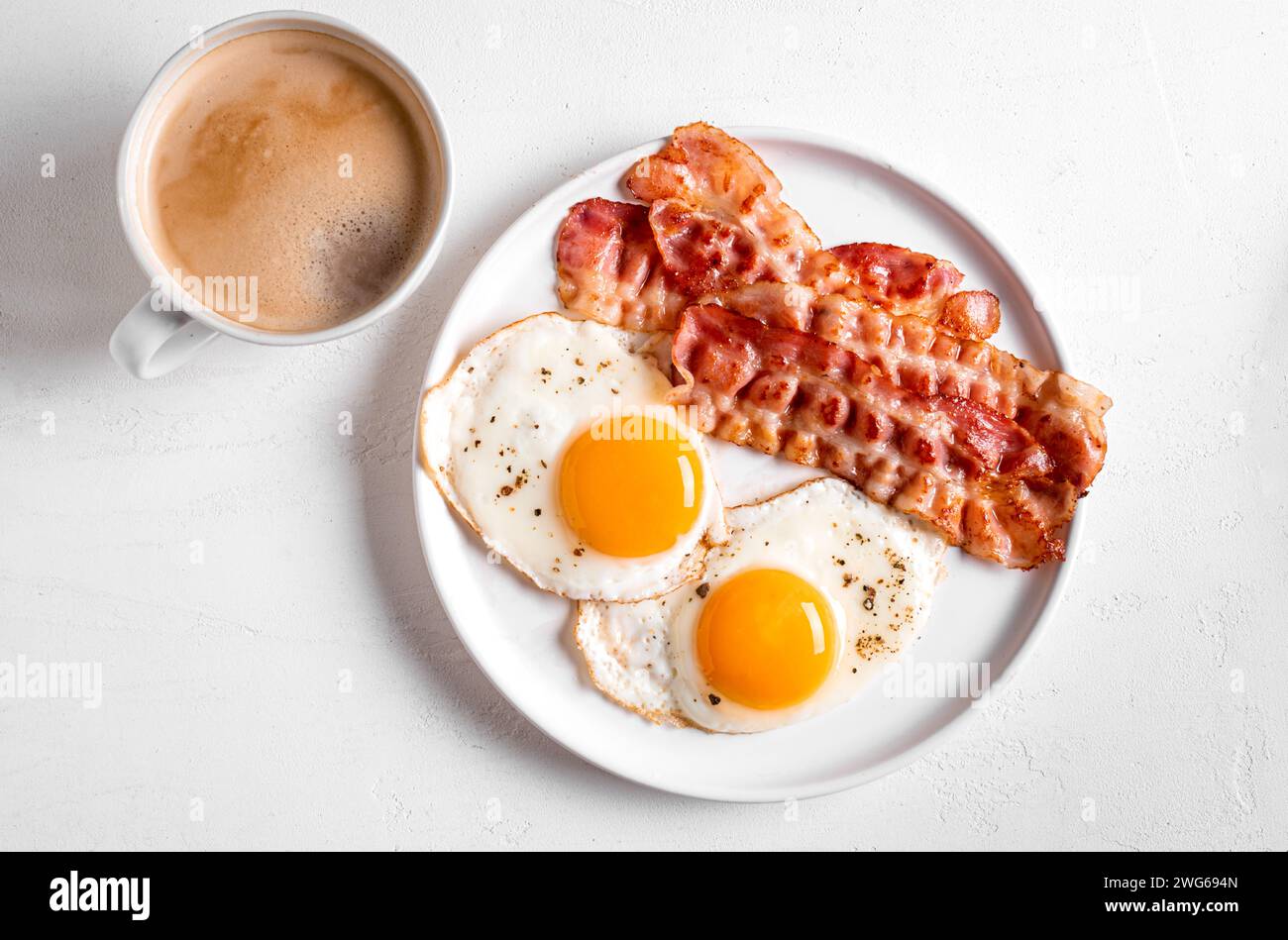 Colazione con uova fritte e pancetta da vicino. Uova fritte al sole con pancetta sul piatto e tazza di caffè del mattino, sano pasto keto. Foto Stock