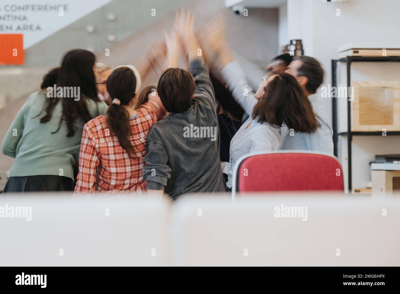 Un gruppo dinamico di colleghi che si esibisce in un'allegra celebrazione dei risultati aziendali in un ambiente di lavoro contemporaneo. Foto Stock