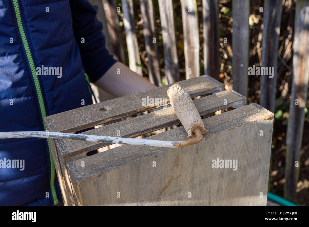 un bambino dipinge una scatola di legno con pennelli in giardino Foto Stock