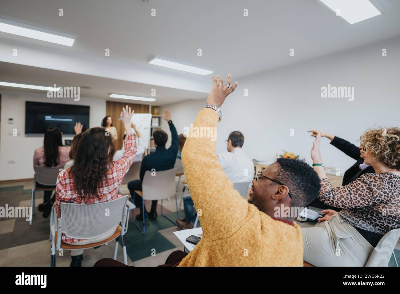 Sessione di workshop interattiva con partecipanti entusiasti che alzano la mano Foto Stock