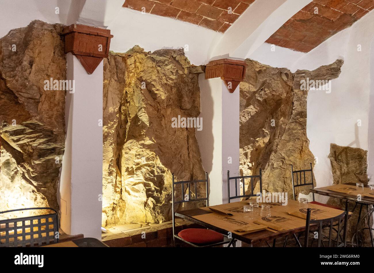 Interno di un ristorante con un muro intagliato nella roccia, Castagneto Carducci, Livorno, Toscana, Italia Foto Stock