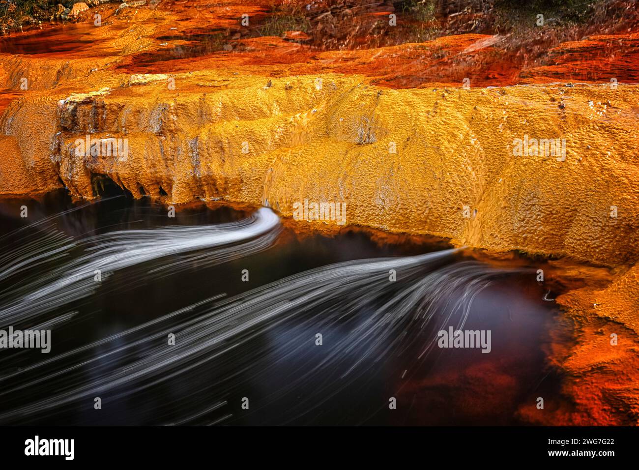 Dettagli vividi dei sedimenti ricchi di ferro e dei tappetini microbici lungo le rive del Rio Tinto. Foto Stock