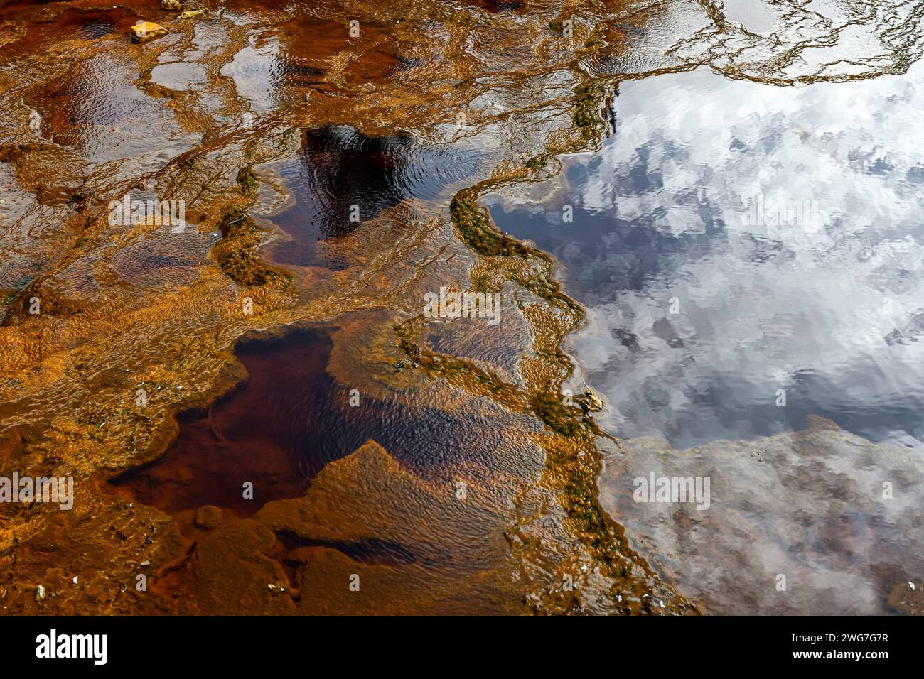 Il Rio Tinto a Huelva, Spagna, espone notevoli depositi di ferro rossi e arancioni e tracce di microrganismi verdi Foto Stock