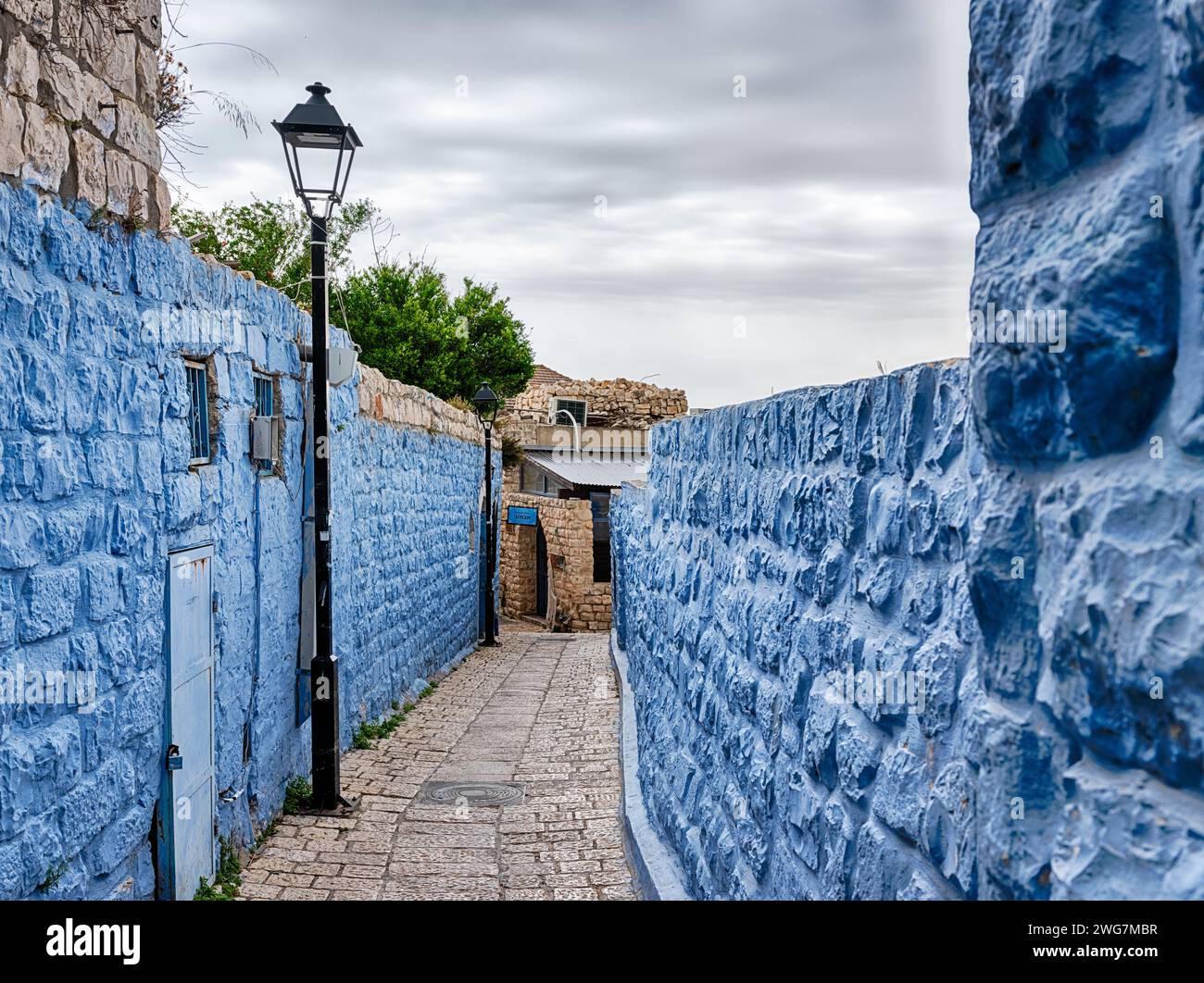 Una stretta passerella serpeggia tra due mura blu nel centro storico di Tzfat, nel nord di Israele. Foto Stock