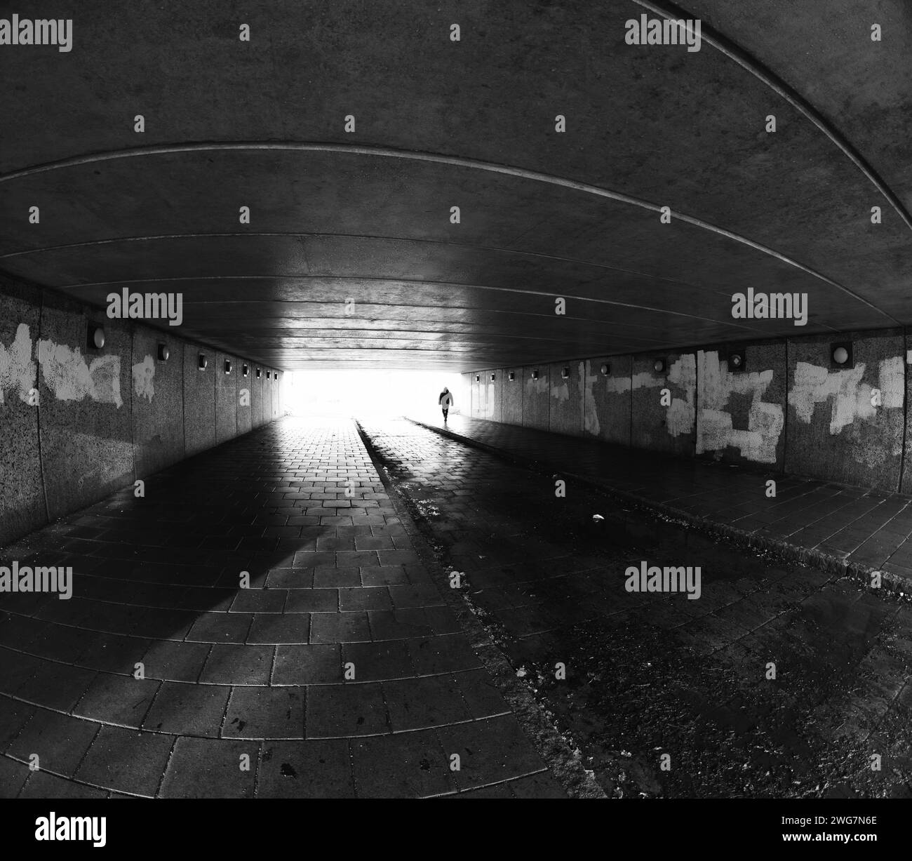 Giovane uomo che cammina attraverso un tunnel urbano Foto Stock