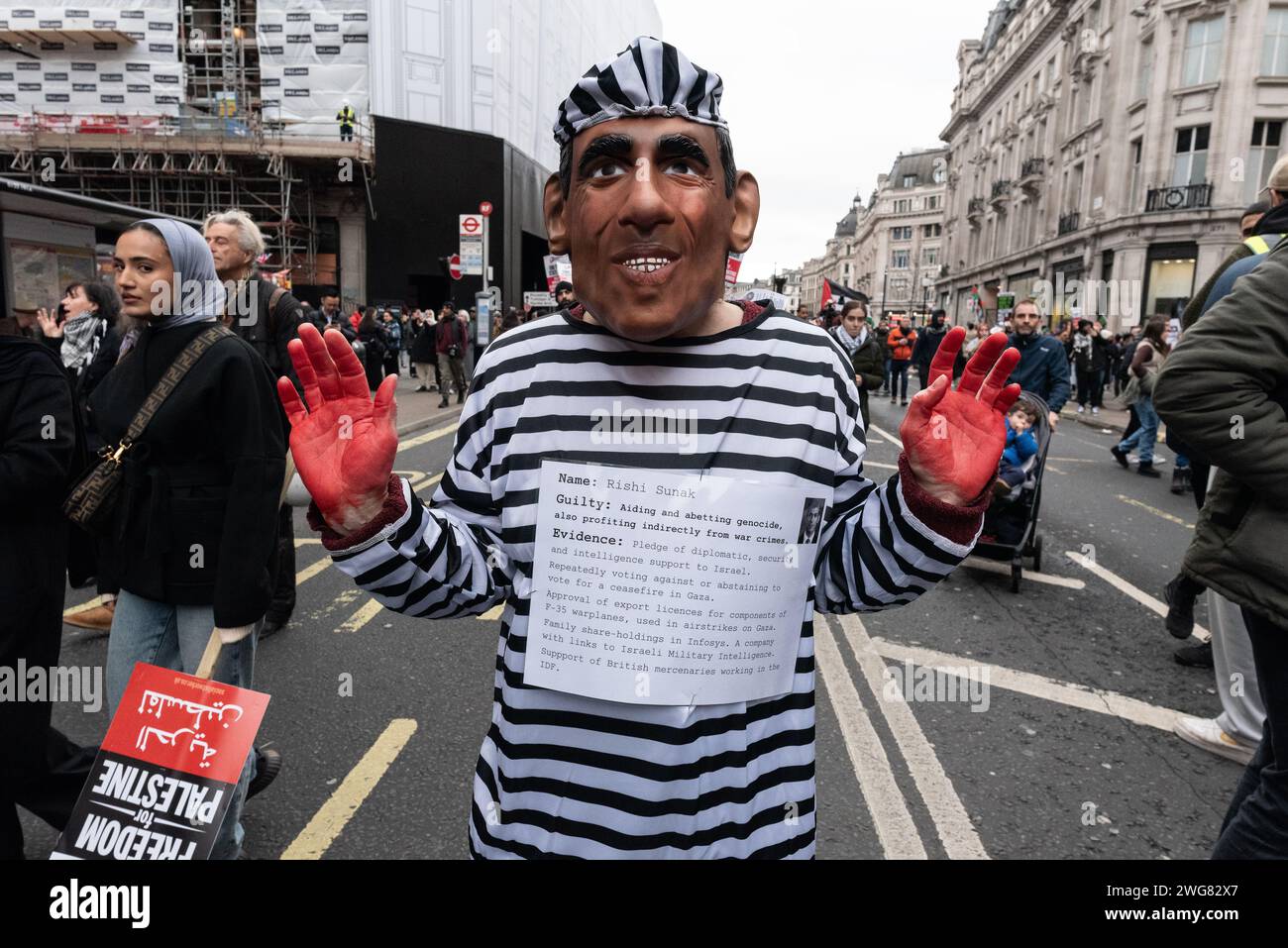 Londra, Regno Unito. 3 febbraio 2024. Un manifestante che indossa una maschera Rishi Sunak, con le mani coperte di sangue falso, tra decine di migliaia di sostenitori palestinesi di una coalizione di gruppi che marciavano dal quartier generale della BBC a Whitehall chiedendo un immediato cessate il fuoco e la fine del bombardamento israeliano, dell'assedio e dell'invasione di Gaza. La protesta ha seguito la determinazione della Corte internazionale di giustizia che è plausibile che il comportamento di Israele a Gaza sia un genocidio. Crediti: Ron Fassbender/Alamy Live News Foto Stock