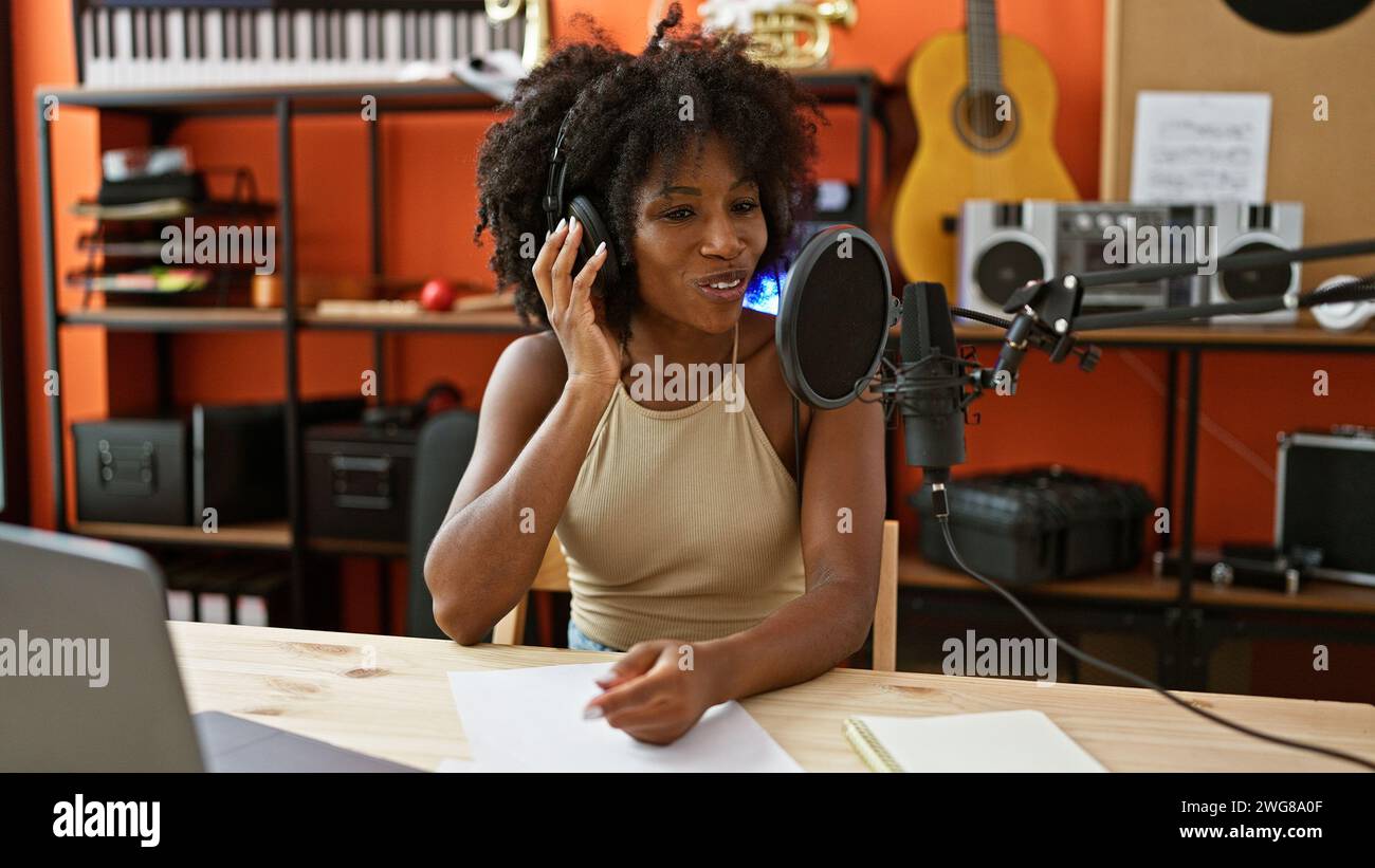Giornalista radiofonica afro-americana che indossa cuffie che parla allo studio radio Foto Stock